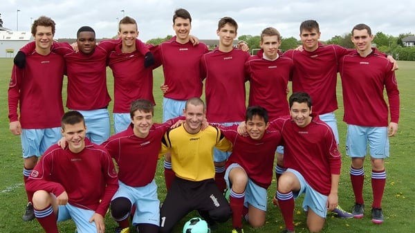 Eine Gruppe von Schülern der CATS Cambridge steht in roten Trikots gemeinsam auf einem Fußballfeld.