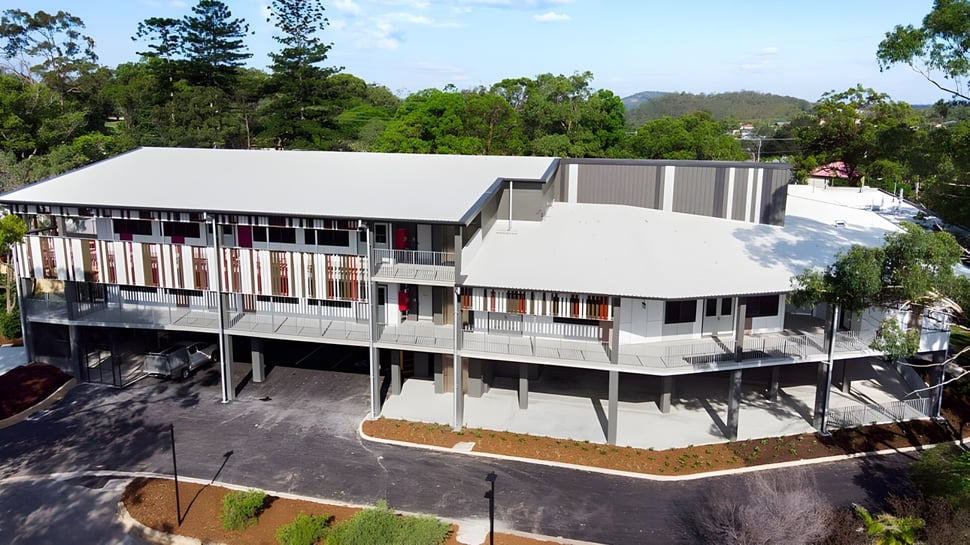 Das moderne mehrstöckige Gebäude der Cavendish Road State High School steht umgeben von bewaldeter Landschaft.