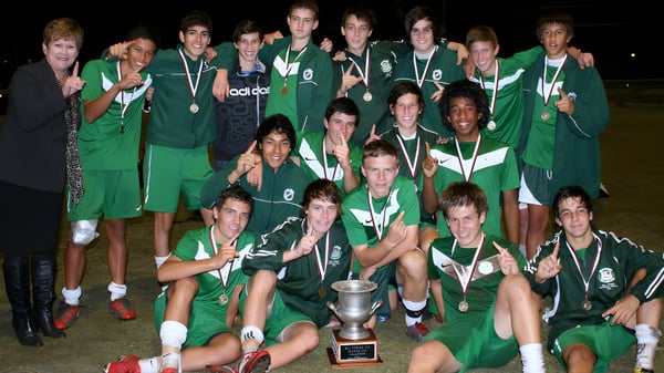 Eine Gruppe junger Athleten feiert mit einem Pokal auf dem Campus der Cavendish Road State High School.