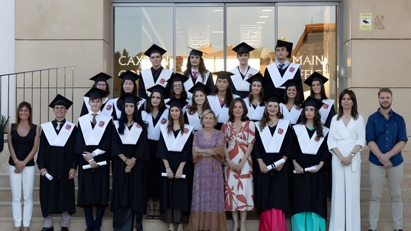 Eine Gruppe Absolventen in akademischer Kleidung posiert vor dem Gebäude mit der Aufschrift Campus Main auf dem Caxton College.