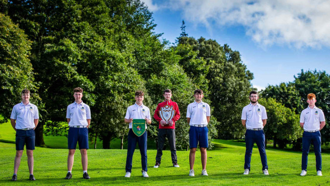 Eine Gruppe Schüler der C.B.S. Roscommon steht auf dem grünen Rasen mit Bäumen und blauem Himmel im Hintergrund.