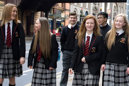 Schüler der CBS Westland Row stehen in Uniform auf einer Straßenszene mit historischen Gebäuden im Hintergrund.