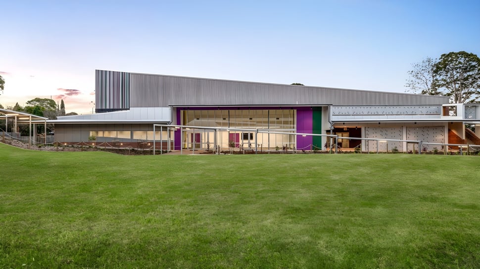 Das moderne einstöckige Gebäude der Centenary Heights State High School mit einer großen Rasenfläche im Vordergrund ist von Bäumen umgeben.