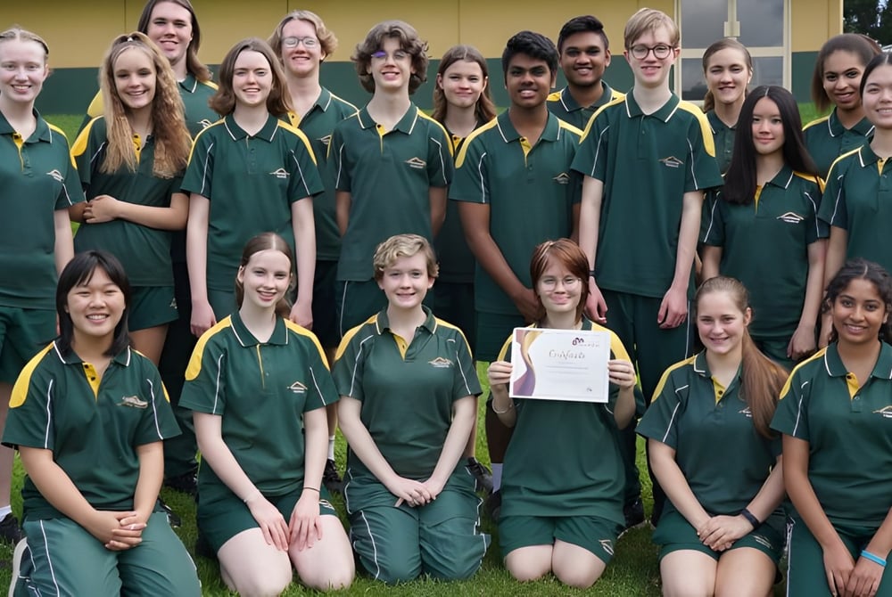 Eine Gruppe Schülerinnen und Schüler der Centenary Heights State High School steht auf einem Grasfeld im Schulgelände.