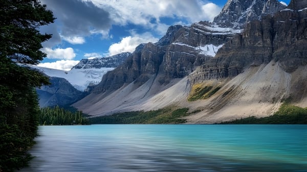 Der ruhige türkisfarbene See vor schneebedeckten Bergen auf dem Gelände des Centennial Collegiate.