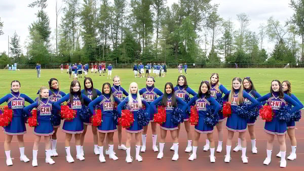 Eine Gruppe von Cheerleadern steht auf dem Rasenfeld auf dem Campus der Centennial Secondary School in British Columbia.