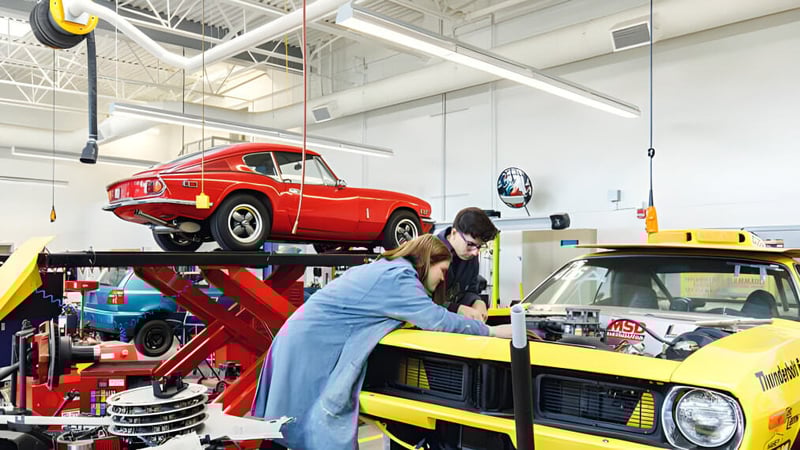 Ein Schüler arbeitet an einem roten Oldtimer auf der Hebebühne in der Werkstatt der Centennial Secondary School in Ontario.