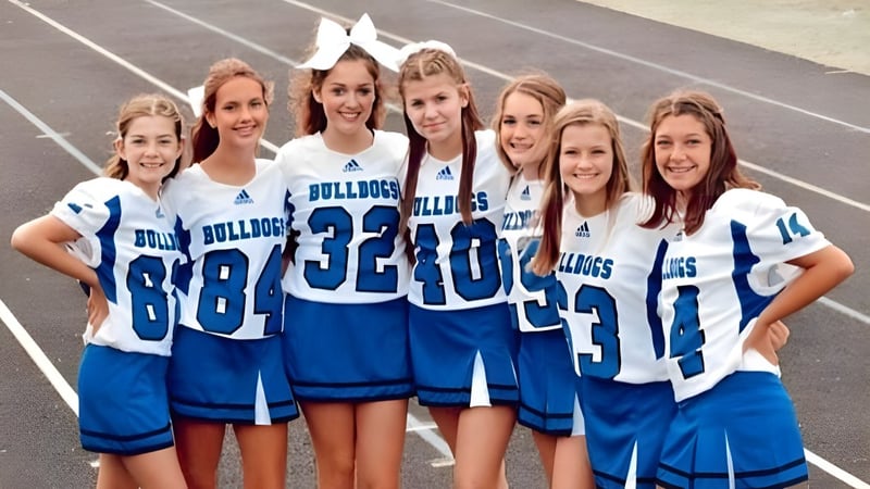 Eine Gruppe junger Athletinnen im Cheerleading-Uniform posiert gemeinsam auf dem Sportplatz der Centerville Senior High School.