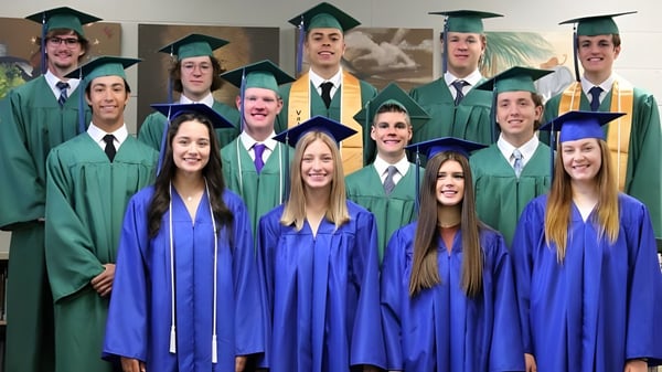Eine Gruppe von Absolventen in grünen und blauen Talaren posiert im Raum mit Dekorationen auf dem Campus der Central Christian School.