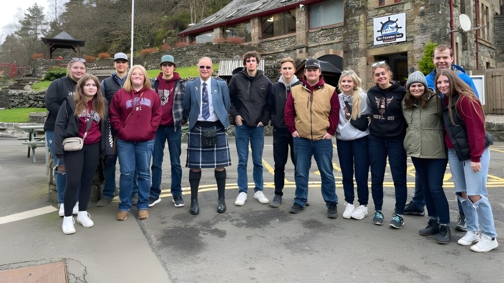 Eine Gruppe Schüler steht vor dem rustikalen Gebäude auf dem Campus der Central High Sedgewick Public School.