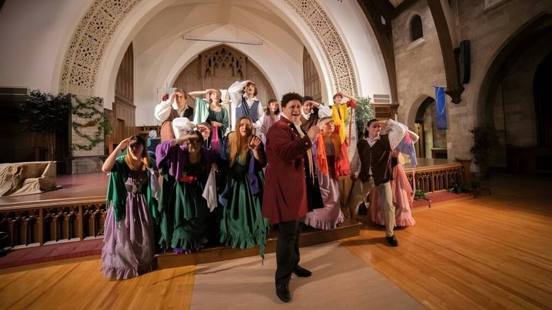 Eine Gruppe von Schülerinnen und Schülern der Central Methodist University steht in farbenfrohen Kostümen in einem prunkvoll verzierten Innenraum mit gewölbten Decken.