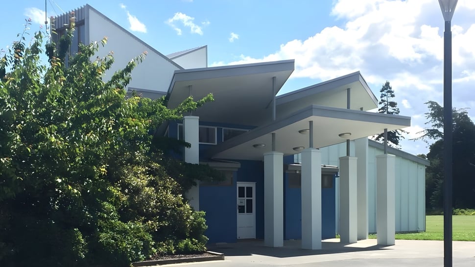 Das moderne Gebäude des Central Southland College mit großen Fenstern und begrüntem Eingangsbereich bei blauem Himmel.