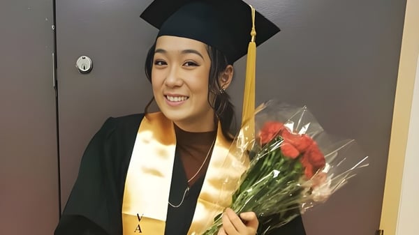 Eine Absolventin der Central Technical School in Talar hält vor einer Tür einen Strauß roter Rosen und lächelt.