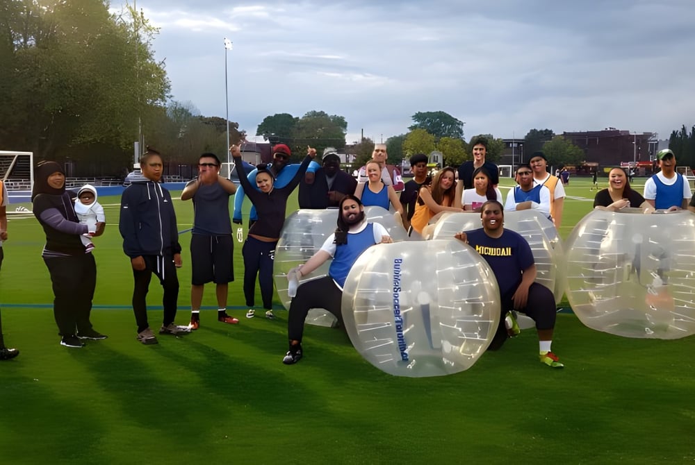 Eine Gruppe Schülerinnen und Schüler der Central Technical School trägt auf einer Wiese aufblasbare Bubble-Suits.