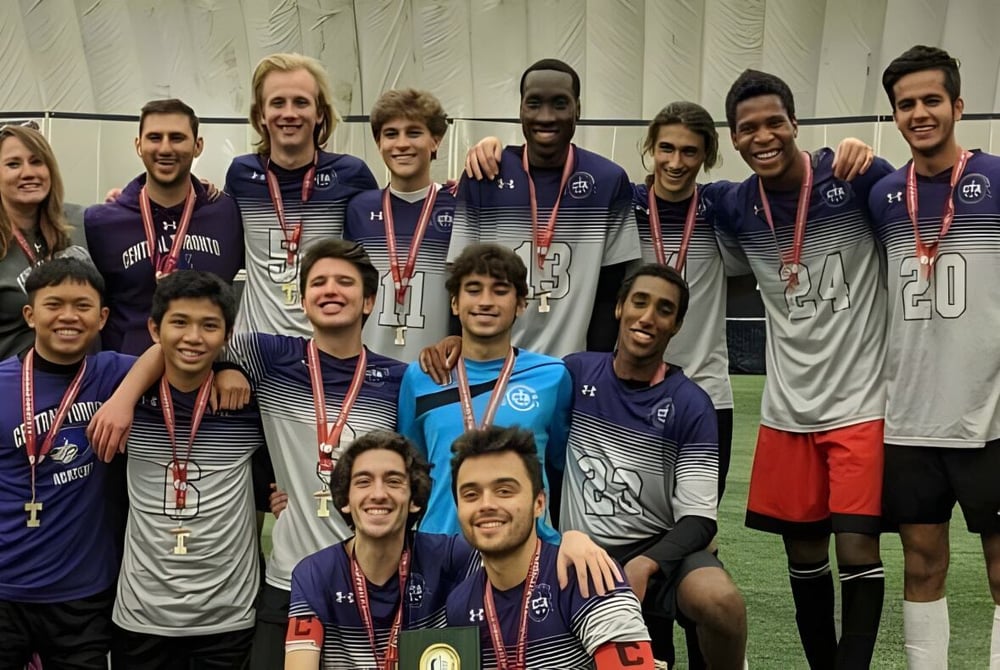 Eine Gruppe von Schülern der Central Toronto Academy posiert in Sportkleidung mit Medaillen vor einer Sportanlage.