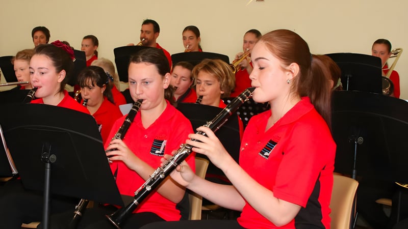 Schüler des Central Yorke School in roten Uniformen spielen als musikalisches Ensemble auf einer Bühne.