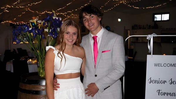 Ein junges Paar steht bei einer Veranstaltung auf dem Campus der Central Yorke School vor einem dekorierten Hintergrund mit Lichterketten und Blumen.