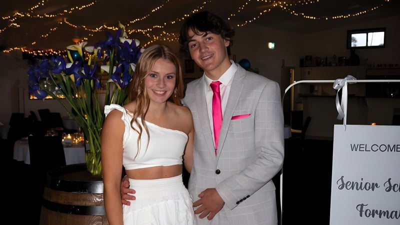 Ein junges Paar steht bei einer Veranstaltung auf dem Campus der Central Yorke School vor einem dekorierten Hintergrund mit Lichterketten und Blumen.