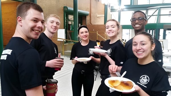 Schüler der Centre High Campus genießen gemeinsam eine Pause mit Snacks im Außenbereich vor einem Backsteingebäude.