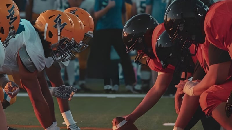 Eine Gruppe von Fußballspielern steht in orange-schwarzen Uniformen auf dem Spielfeld der Chaffey High School.