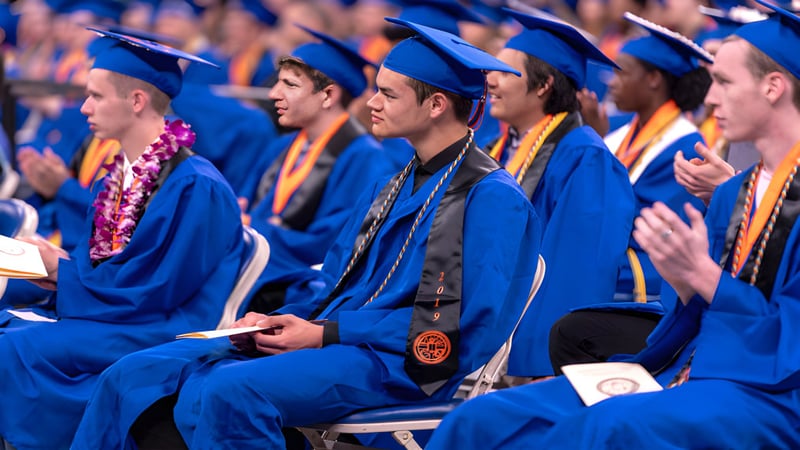 Absolventinnen und Absolventen des Chaffey Joint Union High School District sitzen in blauen Talaren bei der Abschlussfeier im Auditorium.