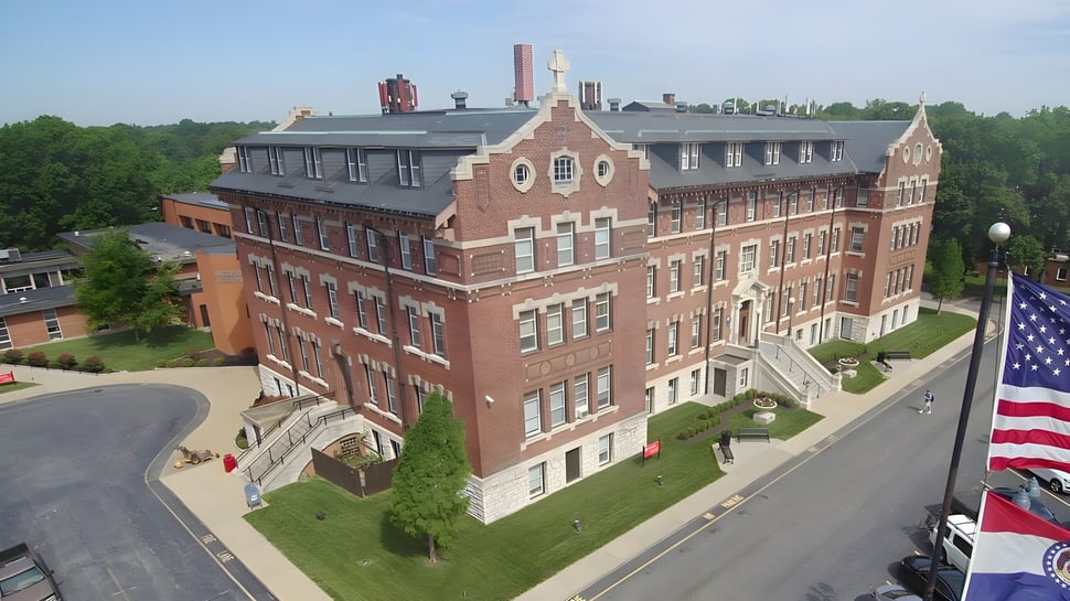 Das große Backsteingebäude mit auffälliger Architektur auf dem Campus der Chaminade College Preparatory School ist von Grünflächen umgeben.