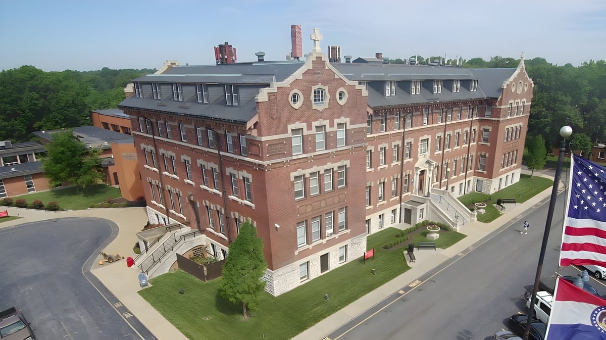 Das dekorative Backsteingebäude der Chaminade College Preparatory School steht umgeben von Grünflächen und einer Straße.