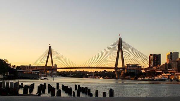 Eine Hängebrücke über einen Fluss vor der Stadtansicht bei Sonnenuntergang in der Nähe des Chancellor State College.