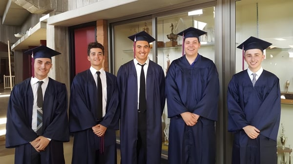 Eine Gruppe von fünf Schülern in Abschlusskappen steht vor einer Glaswand auf dem Campus des Chandler Unified School District.