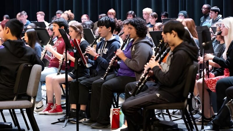 Schüler des Chandler Unified School District sitzen in Reihen und spielen verschiedene Musikinstrumente während einer Musikprobe.