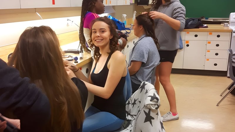 Schülerinnen der Charles Bloom Secondary School interagieren und lächeln im Klassenzimmer.