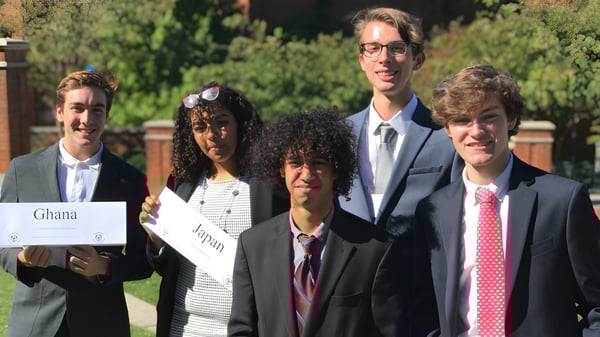 Eine Gruppe Schülerinnen und Schüler der Charlotte-Mecklenburg Schools steht gemeinsam draußen auf einer Wiese mit Bäumen im Hintergrund.