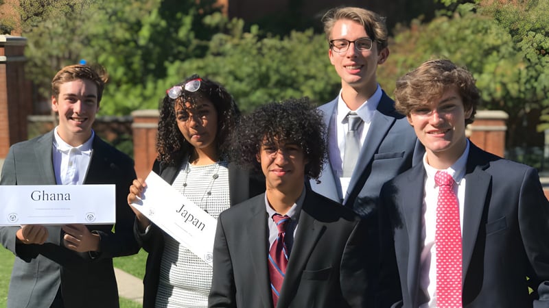 Eine Gruppe Schülerinnen und Schüler der Charlotte-Mecklenburg Schools steht gemeinsam draußen auf einer Wiese mit Bäumen im Hintergrund.