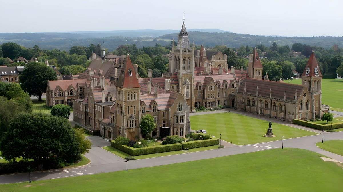 Die Charterhouse School zeigt ein prachtvolles schlossartiges Gebäude mit Türmen und grünen Rasenflächen im ländlichen Umfeld.