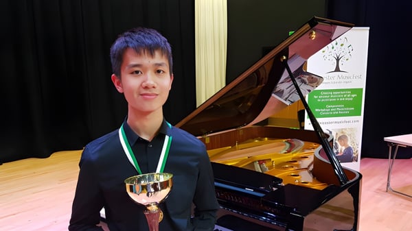 Ein Schüler der Chase Grammar School steht vor einem Flügel und hält einen Pokal in der Hand.