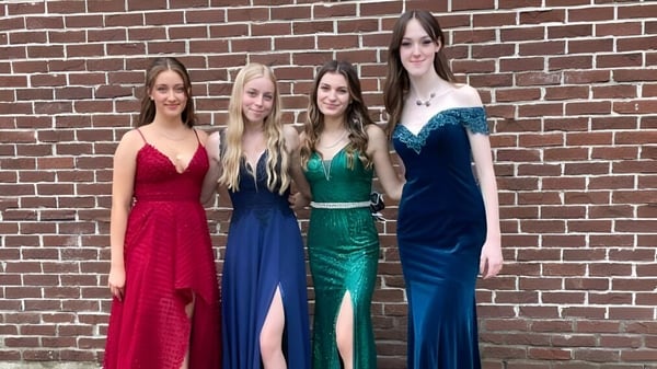 Vier Schülerinnen in formeller Kleidung stehen vor einer Ziegelwand auf dem Gelände der Chateauguay Valley Regional High School.