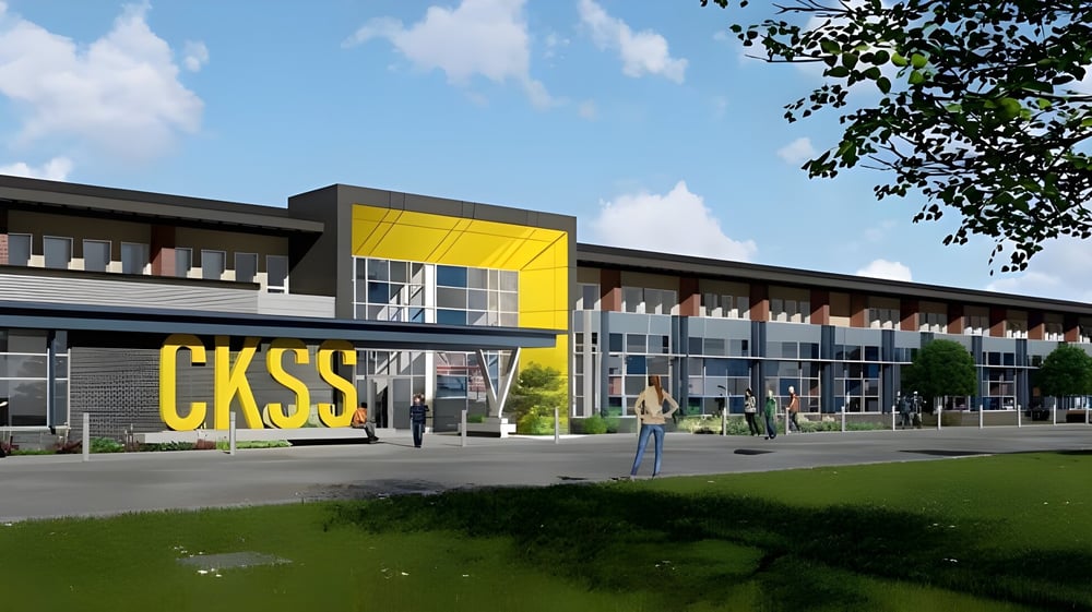 Das moderne mehrstöckige Gebäude der Chatham Kent Secondary School mit einem gelben Schild und umgeben von Grünflächen.