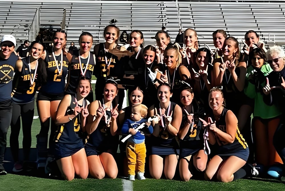 Eine Gruppe junger Athletinnen steht gemeinsam im einheitlichen Trikot auf dem Sportplatz der Chelsea High School.