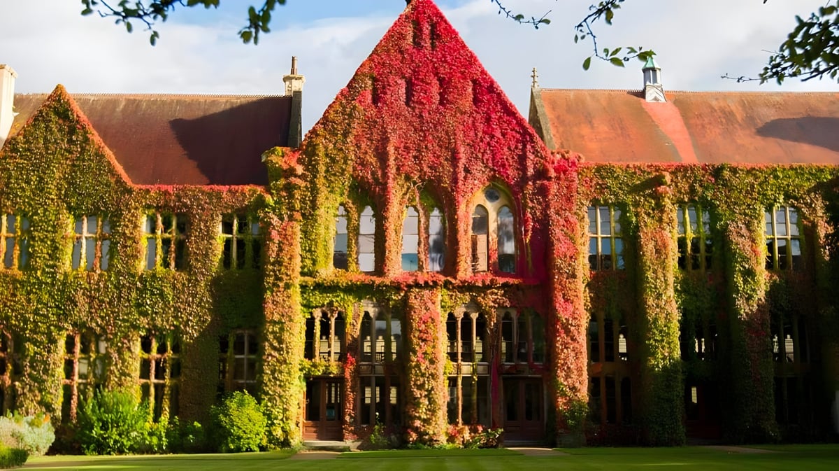 Das historische Gebäude mit roter Fassade befindet sich auf dem Campus des Cheltenham Ladies' College und ist von Grün umgeben.