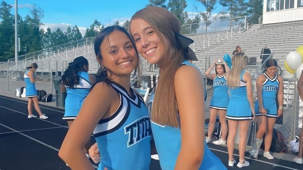 Zwei Schülerinnen in Cheerleader-Uniformen umarmen sich auf dem Sportfeld der Chesterfield School District.