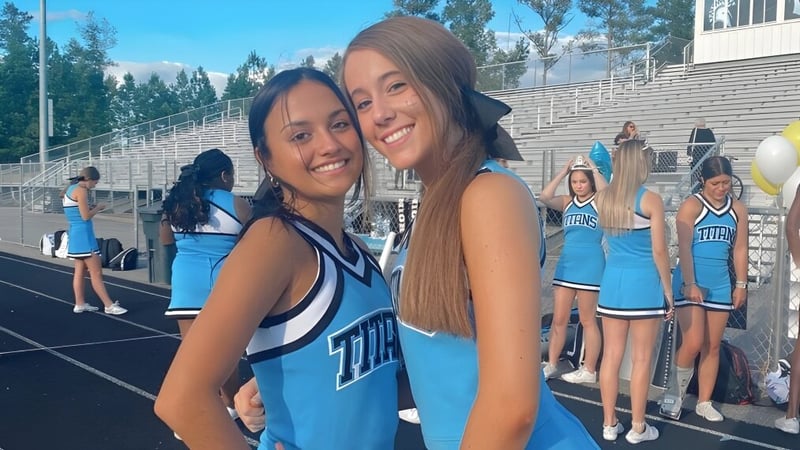 Zwei Schülerinnen in Cheerleader-Uniformen umarmen sich auf dem Sportfeld der Chesterfield School District.