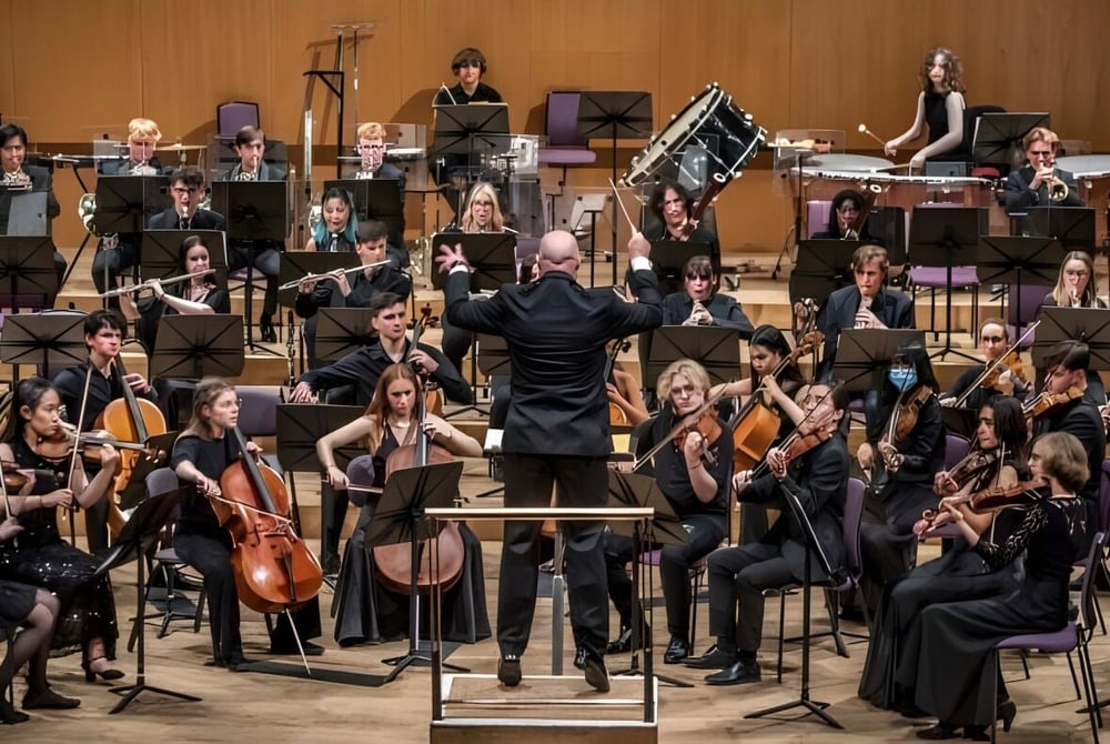 Das Orchester der Chetham’s School of Music führt ein Konzert auf der Bühne unter Leitung des Dirigenten auf.