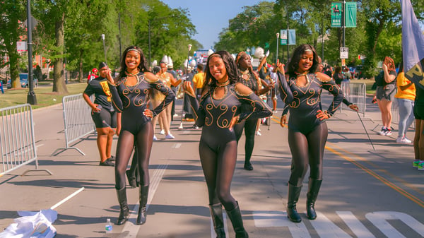 Eine Gruppe Frauen in schwarzen, enganliegenden Outfits geht eine Straße entlang, aufgenommen im Umfeld der Chicago Public Schools.