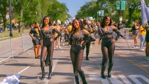 Eine Gruppe Frauen in schwarzen, enganliegenden Outfits geht eine Straße entlang, aufgenommen im Umfeld der Chicago Public Schools.