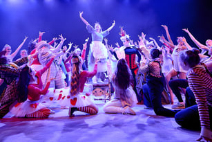 Eine Gruppe von Schülern des Chichester College führt ein farbenfrohes Bühnenstück mit dramatischer Beleuchtung auf.