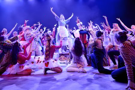 Eine Gruppe von Schülern des Chichester College führt ein farbenfrohes Bühnenstück mit dramatischer Beleuchtung auf.