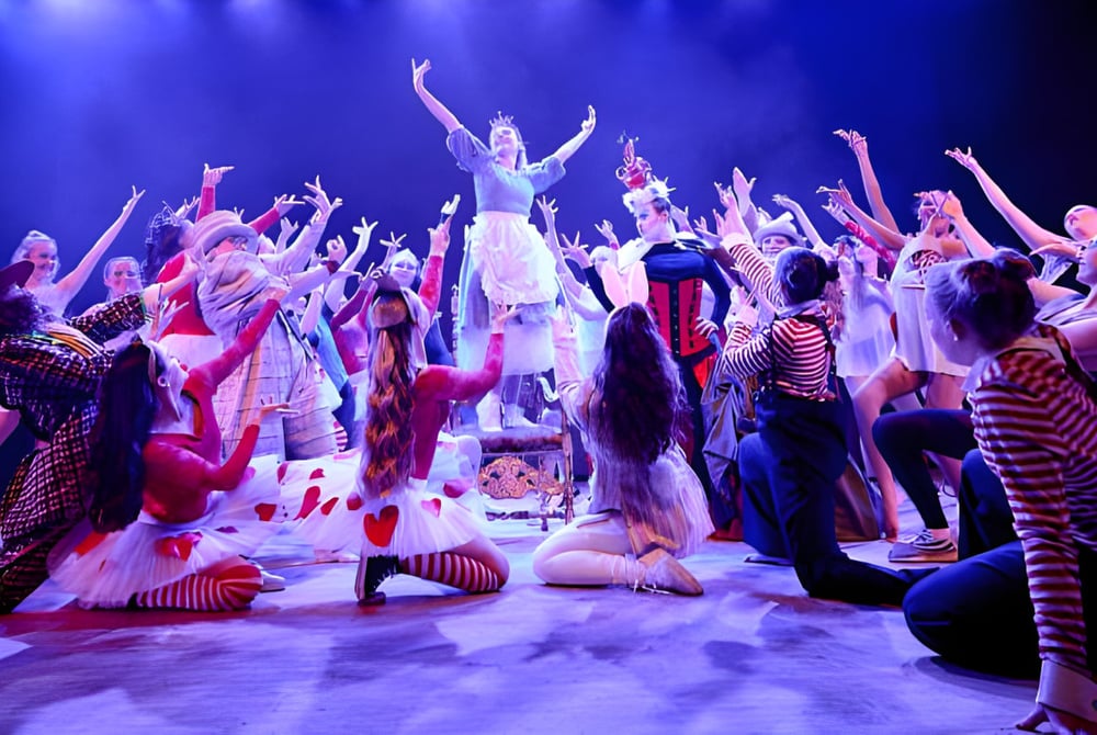 Eine Gruppe von Schülern des Chichester College führt ein farbenfrohes Bühnenstück mit dramatischer Beleuchtung auf.