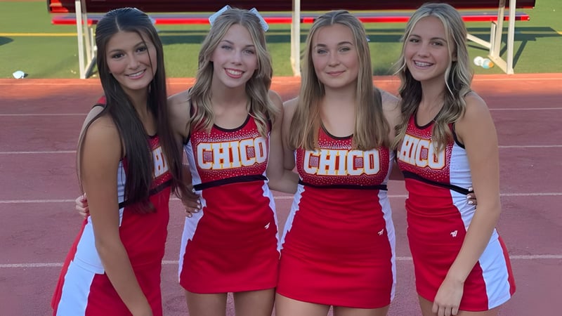 Vier Schülerinnen in roten Cheerleading-Uniformen stehen auf dem Sportfeld des Chico Unified School District.