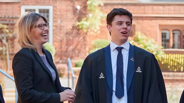 Zwei Schüler stehen vor einem Backsteingebäude auf dem Campus der Chigwell School und führen ein Gespräch.