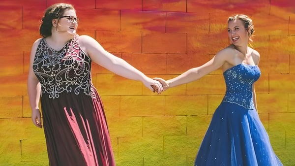 Zwei Frauen in eleganten Kleidern halten sich an der Hand bei einer Veranstaltung der Chilliwack Secondary School.